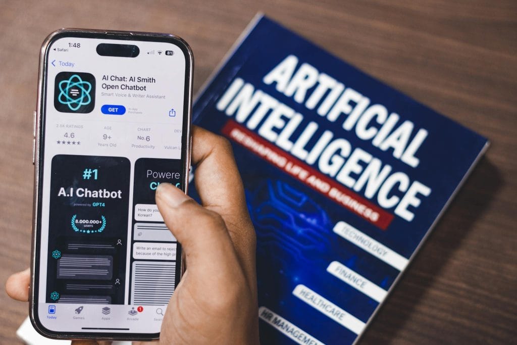 The Essentials of Blogging: Tips and Strategies for Success Smartphone displaying AI app with book on AI technology in background.