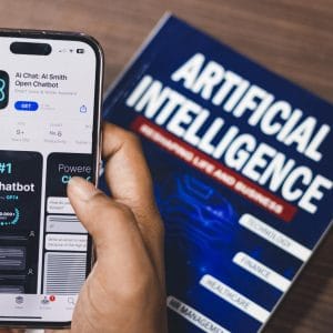 Smartphone displaying AI app with book on AI technology in background.