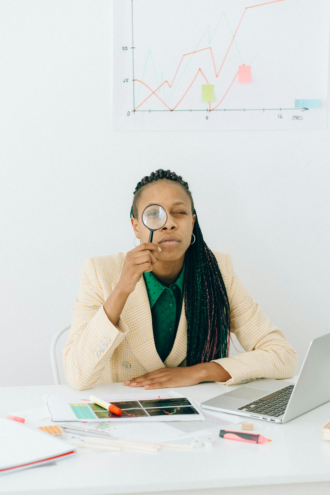 Woman Examining Data Charts With A Magnifying